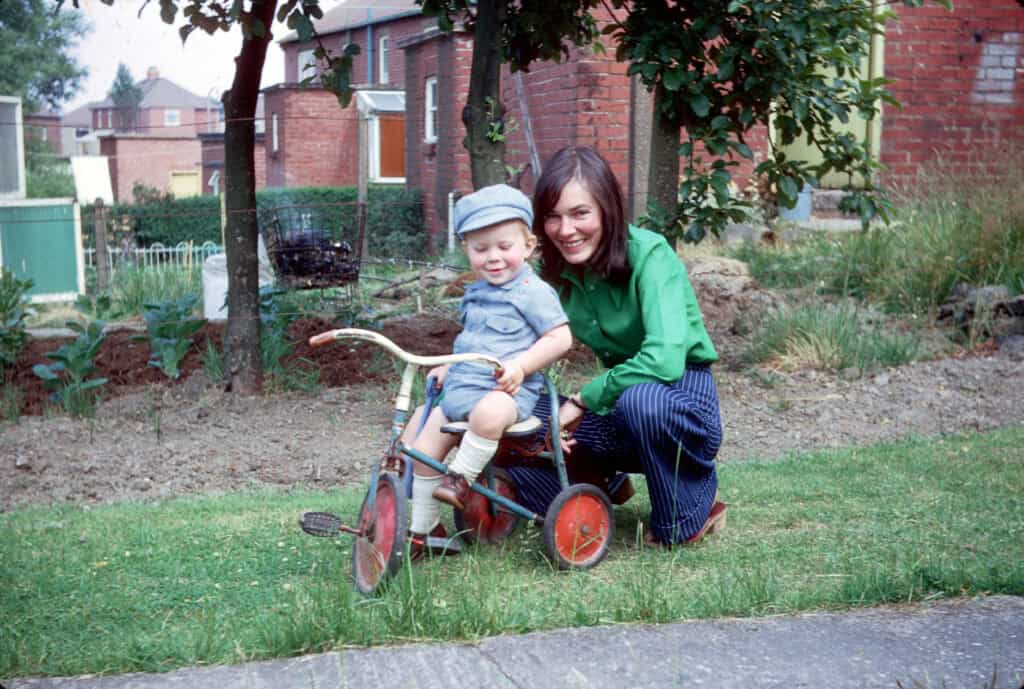 Child riding a tricycle with a smiling woman during Christmas 2023.