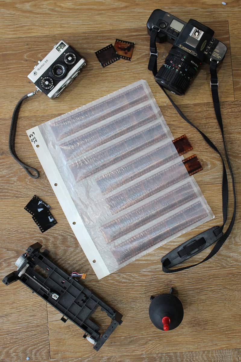 A collection of vintage cameras, film rolls, and accessories for analog photography on a wooden surface.